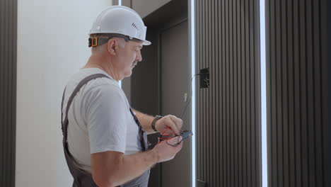 camera moves behind electric checks the operation of the wall control unit of lamps with the system of modern home after installation and repair