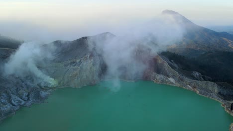 aerial view of sulfur mine with white fog steaming in middle of ijen green acid lake in java indonesia