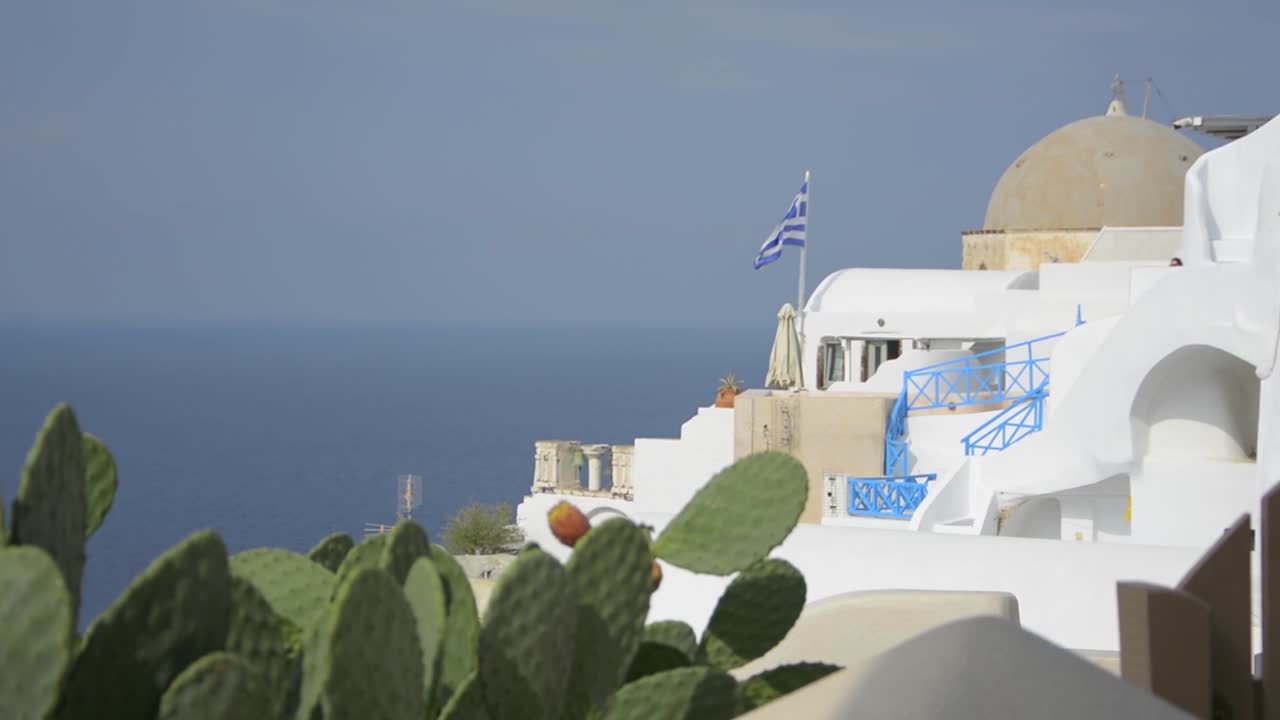 la bandera griega ondeando al viento en la ciudad de oia en santorini, grecia