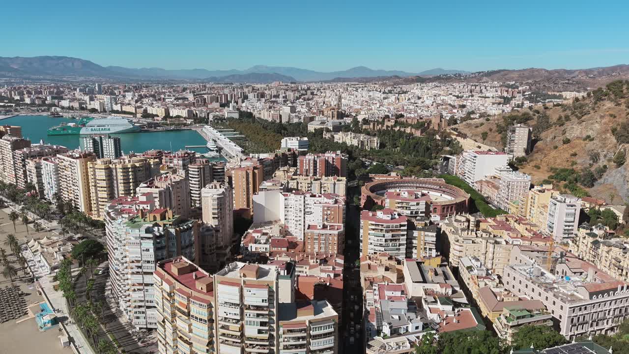 La vista aerea cattura il paesaggio urbano di Malaga, in Spagna, mettendo in mostra i suoi edifici, il porto e le montagne sotto un cielo azzurro in una giornata di sole