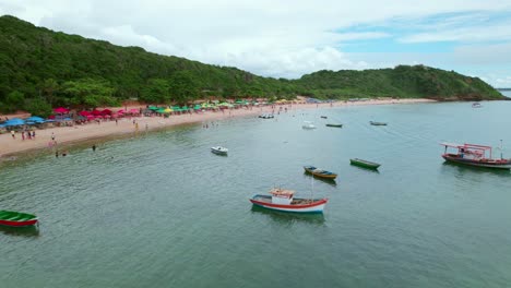 aerial flyover of boats anchored off of tartaruga beach, búzios and swimmers