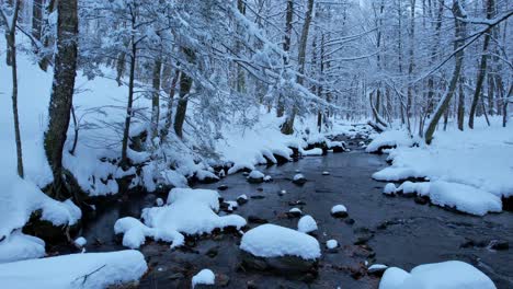 Wunderschöne,-Sanfte-Drohnenaufnahmen-Eines-Verschneiten-Baches-In-Einem-Winterwunderland