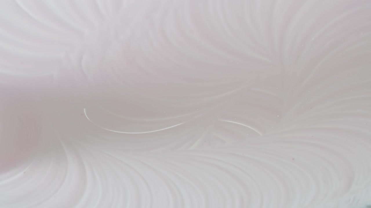 Primo piano astratto di liquido rosa che cade su una superficie bianca e cremosa