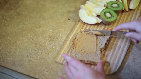 slow motion shot of someone spreading peanut butter onto a piece of whole wheat bread toast