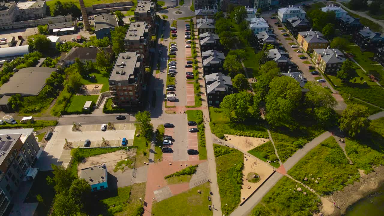 Aerial drone revealing and establishing wide shot of luxury apartment buildings and private houses on a sunny summer peninsula at Paljassaare in north of Tallinn. Shipyard in the horizon background