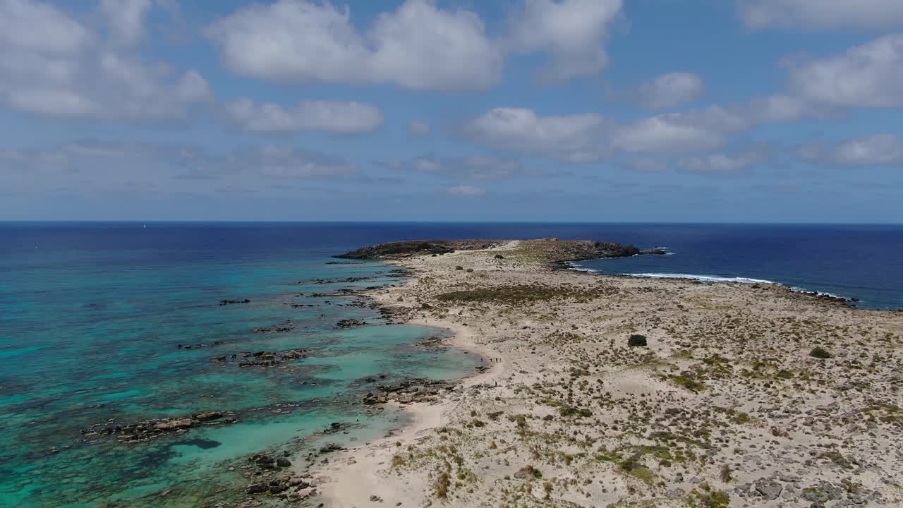 Rock reef beaches of Elafonissi peninsula in Crete Greece with people sand walking below, Aerial flyover shot