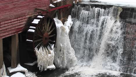 Eine-Nahaufnahme-Von-Wasser,-Das-An-Einer-Mühle-Vorbeifließt,-Deren-Wasserrad-Durch-Gefriertemperaturen-Immobilisiert-Wird?