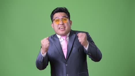 초록색 배경에 젊은 잘생긴 과체중 아시아 사업가