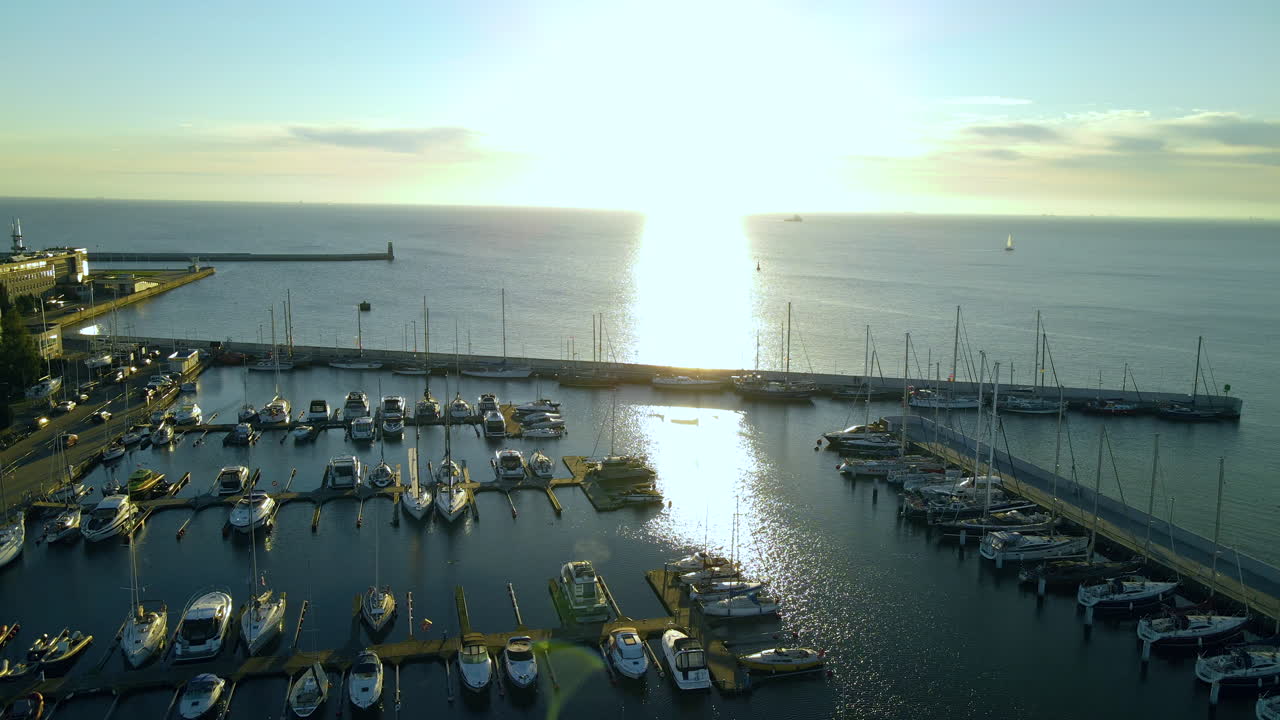 발트해 연안의 잔잔한 바다에 보트와 요트가 정박해 있는 폴란드 그디니아(gdynia)의 마리나 그디니아(marina gdynia) 위로 아름다운 일출 전망 - 풀백 드론 샷