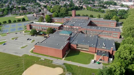 high aerial establishing shot of school, university, college campus with brick academic buildings and sports fields, tennis courts