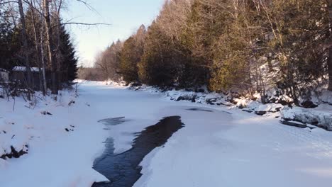 partially iced-over stream in a snow-covered forest, sherbrooke, quebec