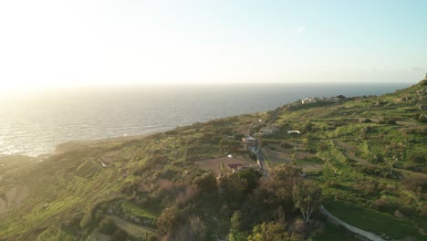 aerial: reveal shot of mediterranean sea and green hill near coastline of malta in winter