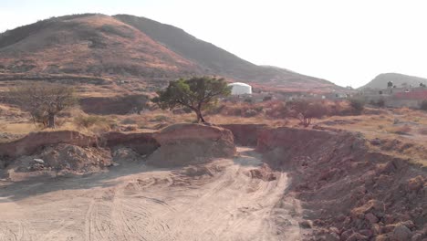 Hill-side-soil-excavated-land-area-with-few-residences-at-Alta-California,-Mexico---drone-flying-track-shot