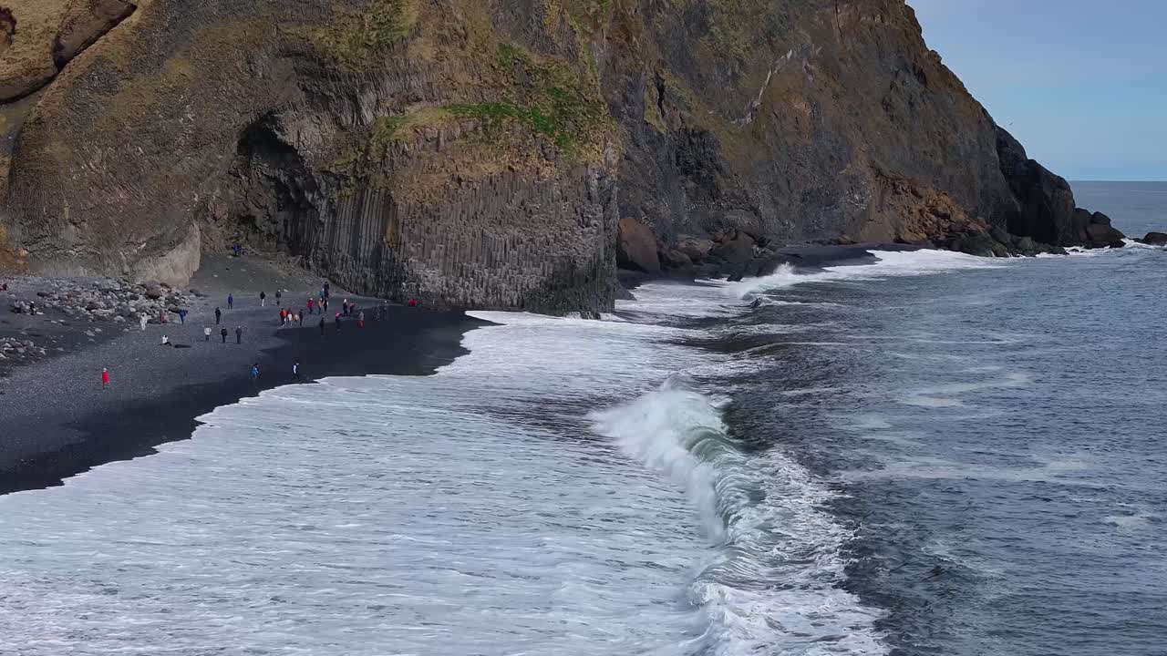 la vista de la gente disfrutando de la experiencia, con las majestuosas montañas, playas tranquilas todo en la impresionante playa de arena negra