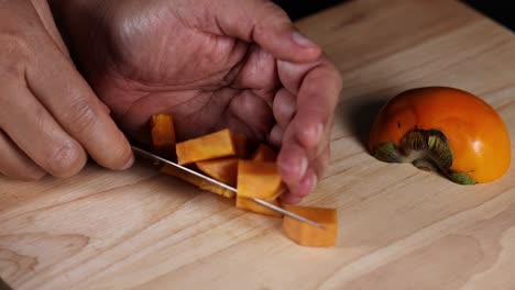 hands cutting persimmon into small cubes