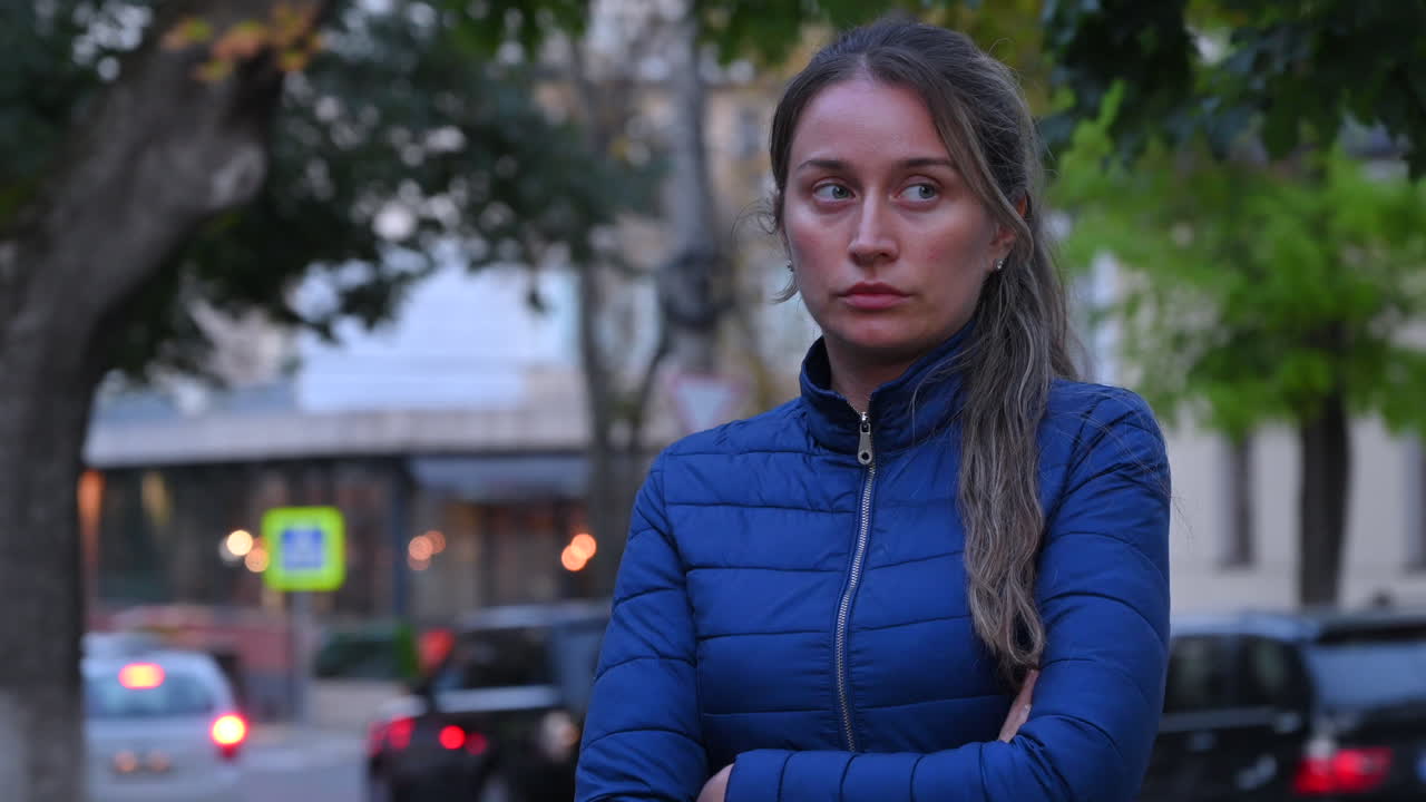 Donna caucasica triste con cappotto blu infreddolita per strada di sera