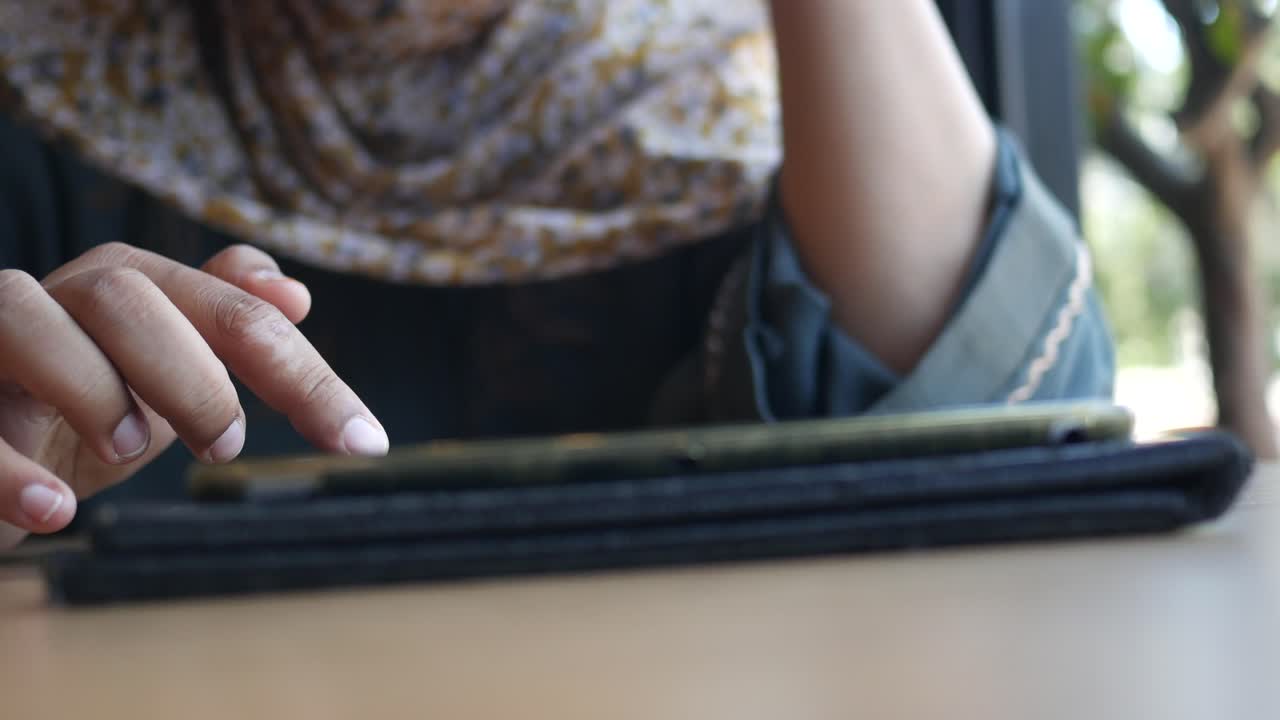 una mujer con hijab usa su teléfono en un café