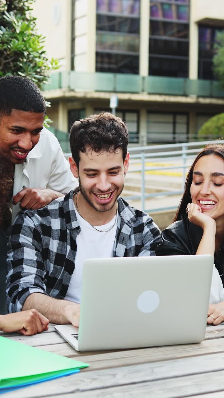 Grupo diverso de jóvenes estudiantes colaborando en un portátil al aire libre