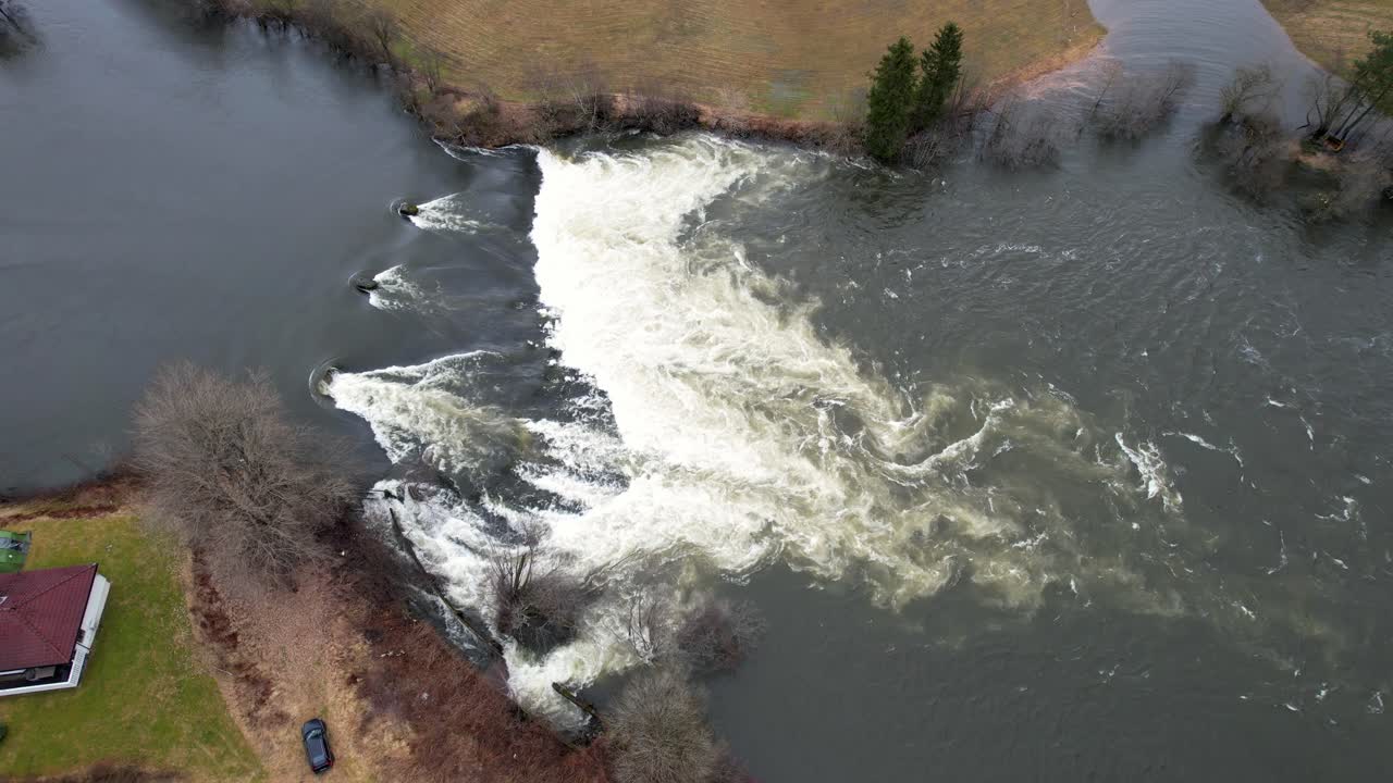 Oversvømmet flod ved Skulestadmo Voss, Norge, med stærk strøm og højt vand efter kraftig regn.