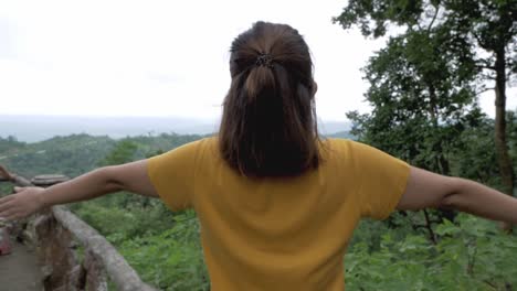 an individual stretching out her hands as she is breathing fresh air from a pristine and clean surroundings amidst nature