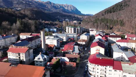 Aerial-flyover-city-of-Sinaia-with-colorful-rooftops-and-green-mountains-in-backdrop---Romania,Europe,-Southern-Carpathians