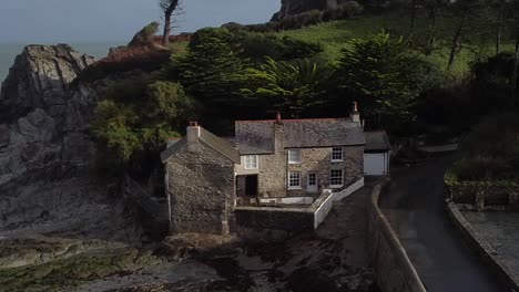 aerial drone close up orbit of an english mill house on the shoreline of a coastal village - lee bay, beach, ilfracombe, devon, england