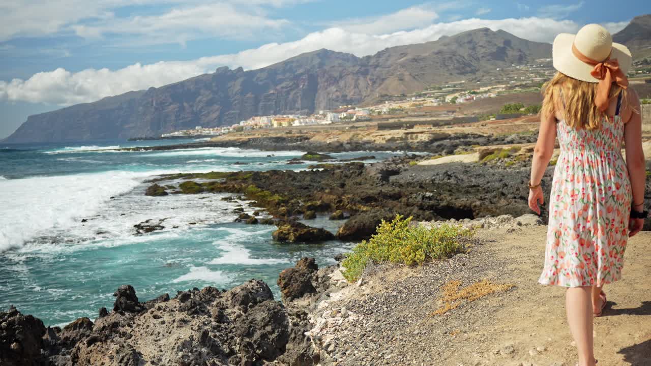 Mujer atractiva y aventurera caminando hacia la costa de Tenerife, de espaldas