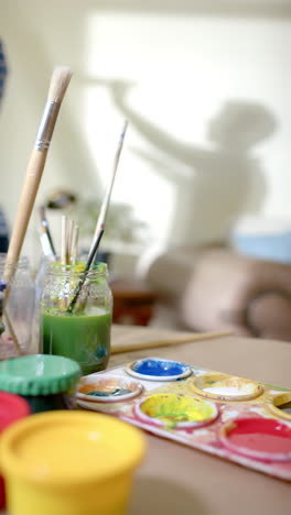 vertical video of senior biracial woman painting at home, slow motion