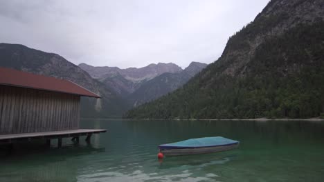 lake with hut and boat and mountains in background