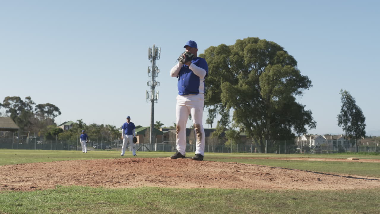 Pitching baseball, male player in uniform on mound during game outdoors