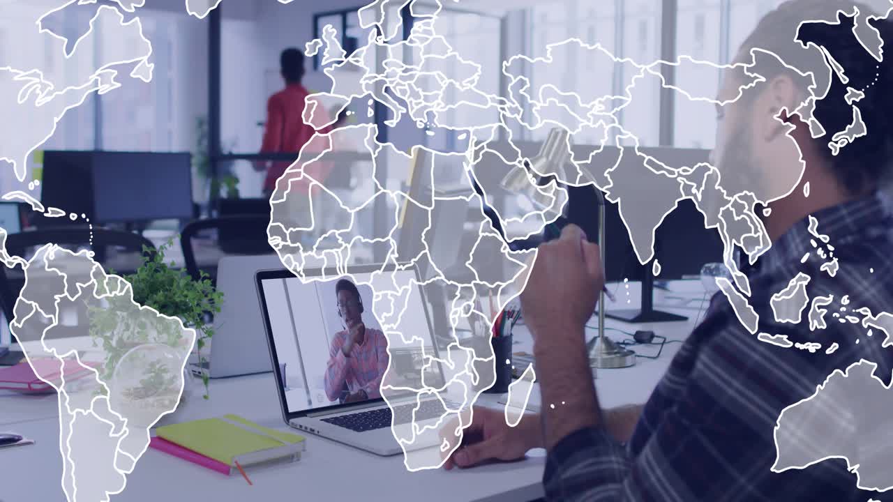 Man at desk holding lamp and gesturing at laptop, remote meeting fading in world map overlay