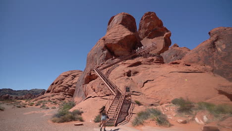 a young woman walking toward stairs of atlatl rock in valley of fire state park