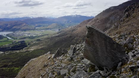 escalador de rocas en lo alto de las montañas en un día nublado en queenstown, nueva zelanda