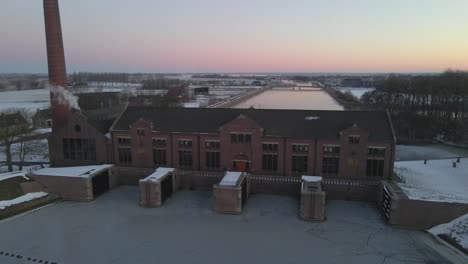 Woudagemaal-building-at-sunrise-in-winter-time-Friesland,-aerial
