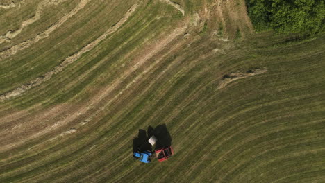 Top-Down-View-Of-Tractor-Producing-Hay-Bales-In-The-Field-In-Oronoco,-Minnesota,-USA---drone-shot