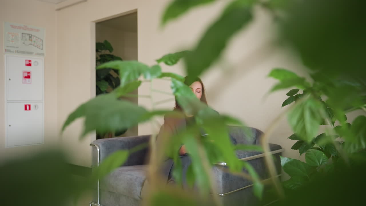 Professional businesswoman with brown hair walking through Eastern European office hallway while holding folder. Profile view captures confident stride in gray formal suit