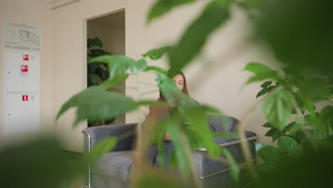 professional businesswoman with brown hair walking through eastern european office hallway while holding folder. profile view captures confident stride in gray formal suit