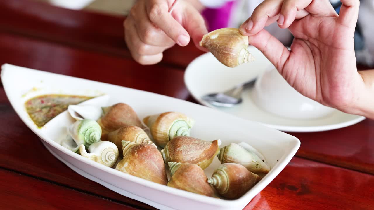 Hands savoring boiled wing shell seafood dish