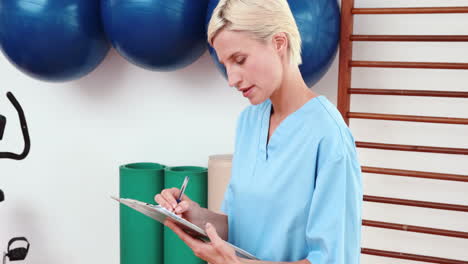 smiling therapist writing on clipboard