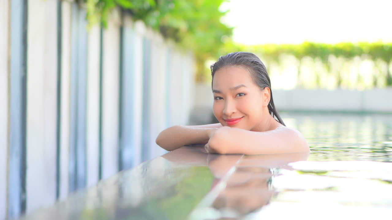 미소로 카메라를 바라보며 수영장에서 즐기는 행복한 이국적인 여성, 슬로우 모션 풀 프레임
