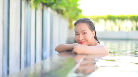 Mujer-Exótica-Feliz-Disfrutando-En-La-Piscina-Mirando-A-La-Cámara-Con-Una-Sonrisa,-Fotograma-Completo-A-Cámara-Lenta