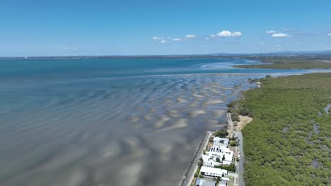 Drone-Aéreo-Disparado-Sobre-La-Playa-De-Beachmere-Y-Bancos-De-Arena,-Barcos-En-El-Río-Que-Se-Abre-Hacia-La-Bahía-De-Moreton-Del-Océano