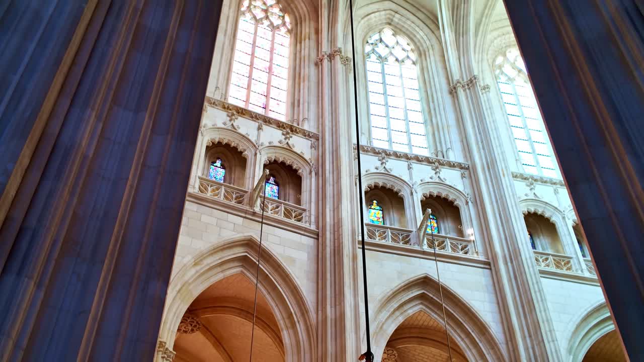 Interno della Cattedrale dei Santi Pietro e Paolo che mostra alti archi gotici, soffitti a volta e un lampadario ornato a Nantes, Francia.