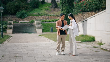 young colleagues discussing documents at street vertical. couple looking papers