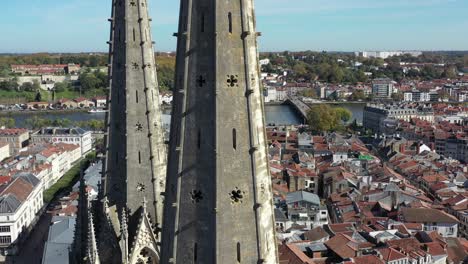 drone flying around gothic spiers of bayonne cathedral with cityscape, france