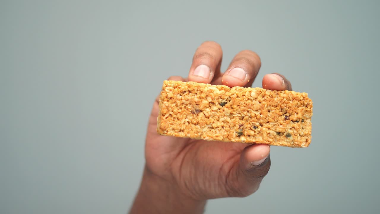 A hand holding a granola bar