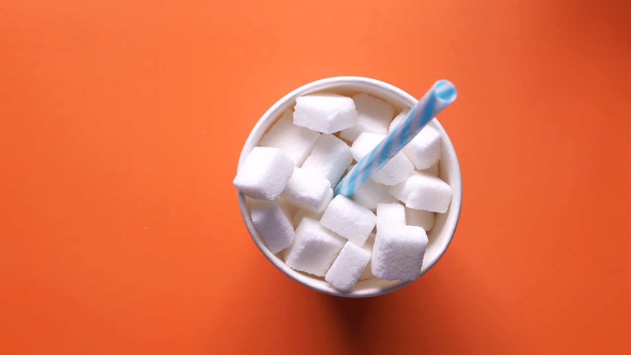 cubos de azúcar en una taza de papel con una pajita