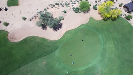 ángulo-Alto-Aéreo,-Larga-Distancia,-Mientras-Un-Golfista-Se-Prepara-Para-Lanzar-Otro-Golfista-Se-Aleja-De-Un-Putt-Perdido-Hace-Mucho-Tiempo,-Scottsdale,-Arizona