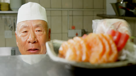 male chef serving a plate with sushi in kitchen 4k