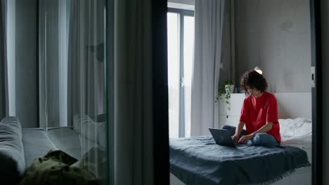 mujer trabajando en una computadora portátil en un dormitorio acogedor
